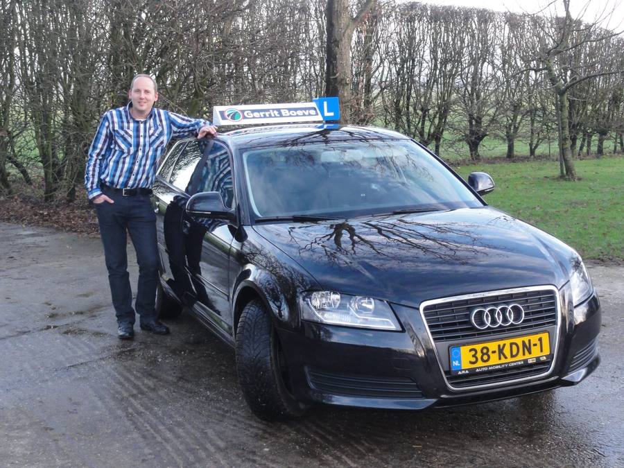 Gerrit Boeve, rijinstructeur en eigenaar van Autorijschool Boeve, naast zijn lesauto